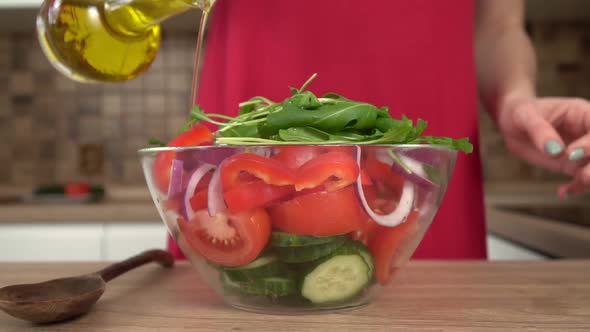 A Woman in the Kitchen Pours a Vegetable Salad with Olive or Sunflower Oil