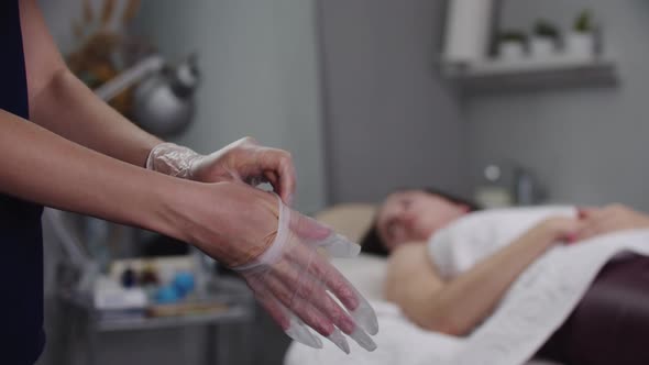 Woman Massagist Putting on Gloves Before Starting the Procedure