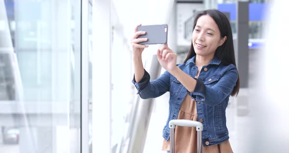 Woman travel in Hong Kong and taking photo by cellphone in airport 