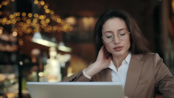 Business Lady with Pain in Neck Using Laptop at Cafe