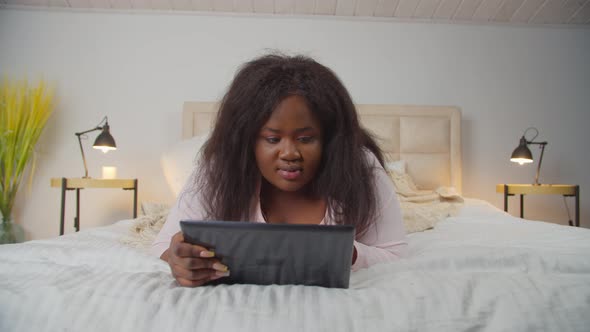 Woman in Pajamas Working with Tablet Pc on Bed