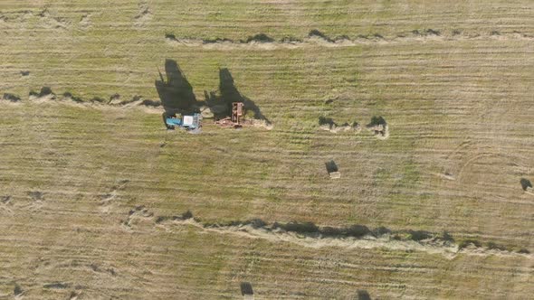 Aerial View of Tractor with Hay in the Field. Bales of Hay Stacked in the Trailer. Agricultural Work