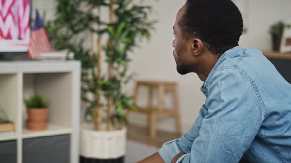 Tracking video of black man drinking coffee and watching TV. Shot with RED helium camera in 8K.