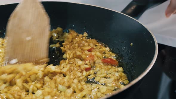 The Cook Prepares Grazing Onions in the Kitchen in a Frying Pan with a Comfortable Handle Stirring