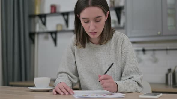 Young Woman Reading Financial Documents in Living Room