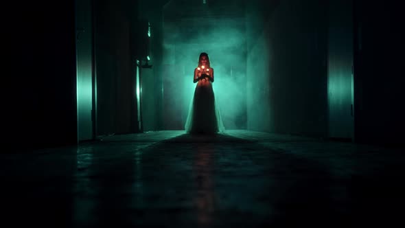 Zombie Woman Walking with Burning Candles in Dark Corridor