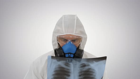 Medic in White Hazmat Protective Suit Checking Lungs X-ray Looking for Epidemic Virus on Gradient
