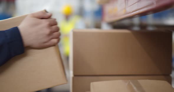 Close Up of Warehouse Worker Putting Cardboard Box on Shelf