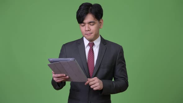 Young Handsome Asian Businessman Using Digital Tablet