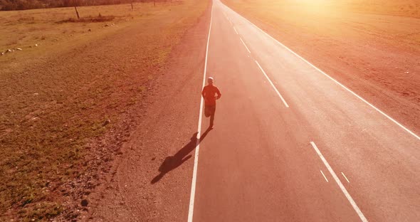 Low Altitude Flight in Front of Sporty Man at Perfect Asphalt Road