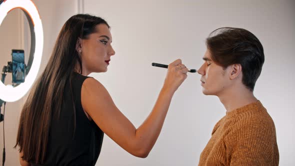 Woman Make Up Artist Applying Powder on the Face of Male Model Using a Brush