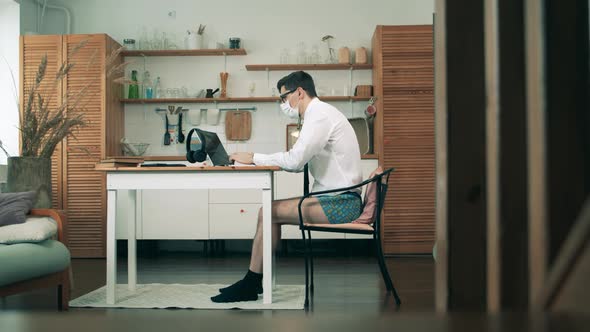 Workimg From Home During Coronavirus Pandemic. A Man with No Pants on Is Working on a Computer From