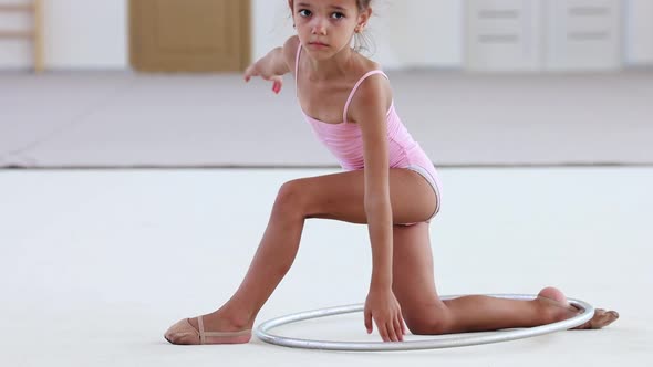 A Little Acrobatic Girl Raising Up a Hoop with Her Leg in Ballet Studio