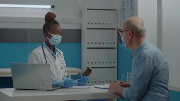 African American Woman Working As Doctor Holding Bottle of Pills