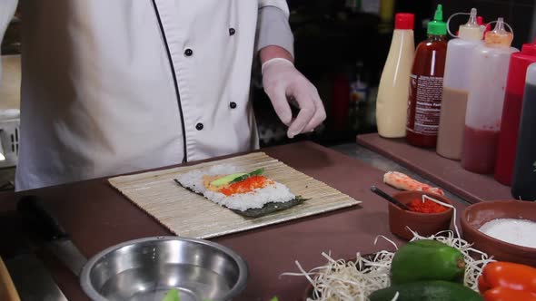 Chef Making Delicious Sushi Rolls With Cucumber and Red Caviar