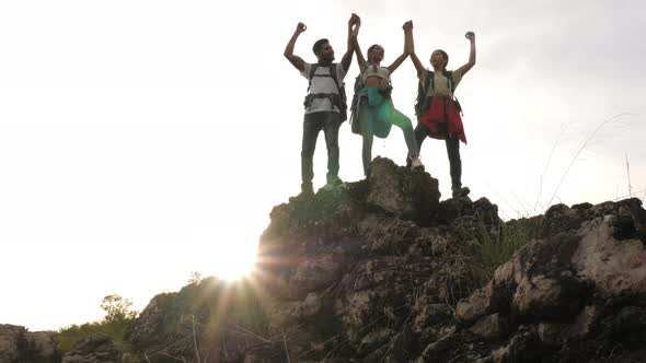 A group of trekkers with backpacks proudly arrive at the top of the mountain.