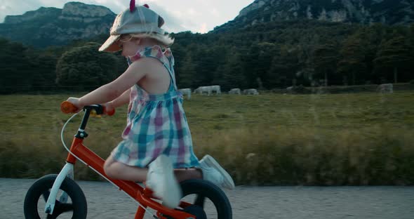 Carefree Happy Toddler Girl Ride Balance Bike on Summertime Vacation in Village