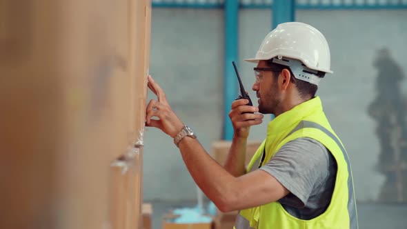 Professional Cargo Worker Talks on Portable Radio to Contact Another Worker