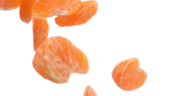 Closeup of the Peeled Tangerine Pieces Falling and Rotating on White Background