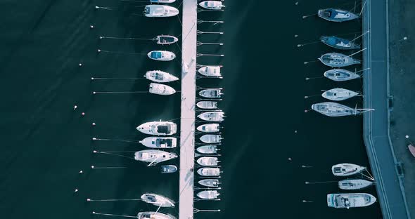 Aerial tracking shot looking directly down at jetty with boats moored.