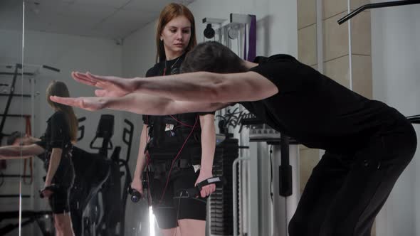 Man Coach Explaining the Exercise to the Young Woman in an EMS Costume