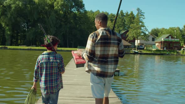 Back View of Multicultural Family with Fishing Rods Going for Angling on Pond