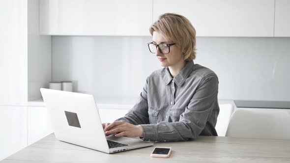 Short Haired Businesswoman Types on White Laptop at Table