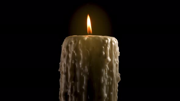 An old and melted candle rotates in front of a black background