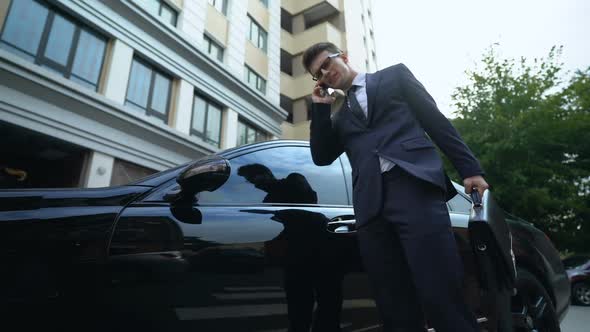 Anxious Businessman Getting in Car Talking on Phone