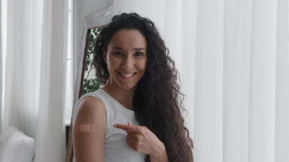 Happy Smiling Hispanic Woman Patient Showing Medical Patch on Shoulder After Injection From Flu