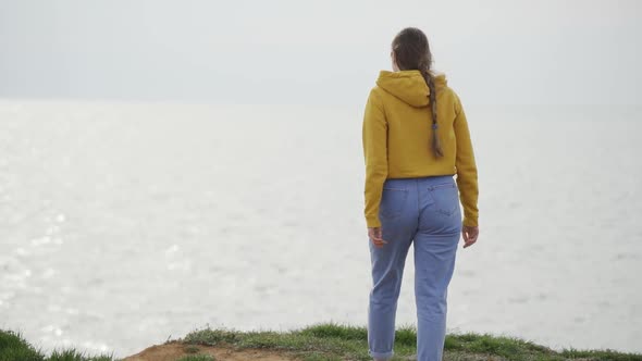 A Woman Walks Up to the Sea and Spreads Her Arms to the Sides to Enjoy the Seascape and Fresh Air