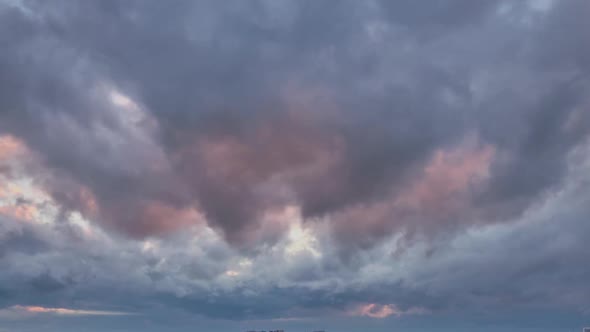 Dark rain clouds in the red light of the setting sun, timelapse