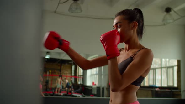 Determined Sporty Fit Black Female Fighter Exercising Punches with Boxing Bag