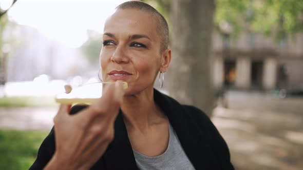 Pretty bald woman recording voice message on phone