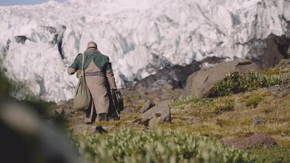 Traveller Carrying Guitar Case On Rocky Hill Next To Glacier