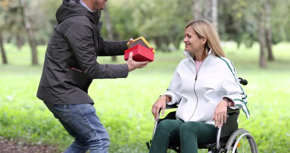 Young Man Giving Gift to Disabled Woman in Wheelchair in Park  Movie