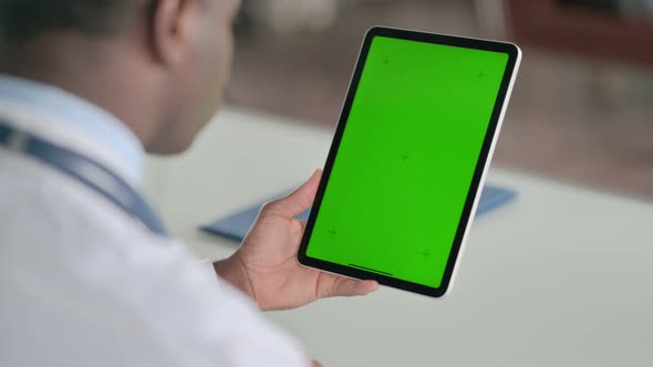 Rear View of African Doctor Using Tablet with Green Chroma Screen
