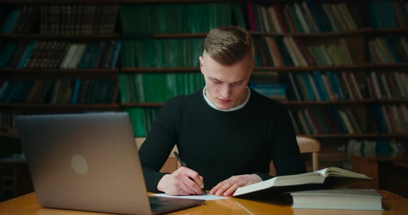 The Guy Is Reading a Book and Makes Notes in the Librery. Education in the Library. 