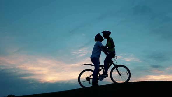 Kiss of Romantic Young Couple on Bicycles Against Sunset