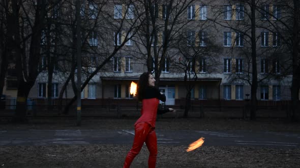 Front View of a Professional Fire Juggler Girl Performing at Night