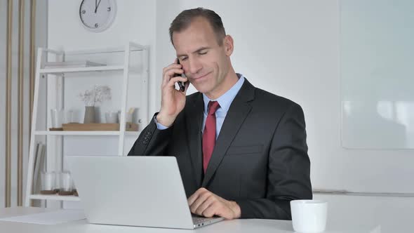 Middle Aged Businessman Talking on Phone Negotiating with Customer