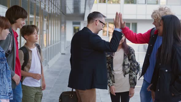 Mature Teacher Talk to Multiethnic Students and Share High Five After Lesson