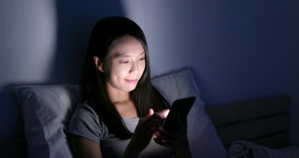 Woman use of smart phone on bed at night