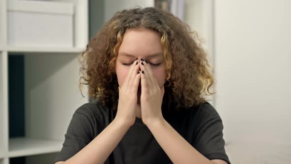 Teenage Girl Sits Alone and Cries Covering Her Face with Her Hands