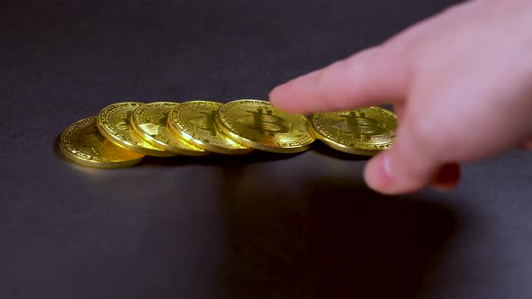 Man Lays Out Bitcoin Coins and Then Takes One Coin From the Pile