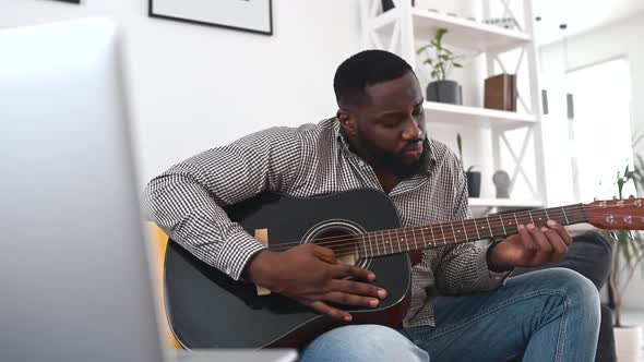 An African American Guy is Playing Guitar