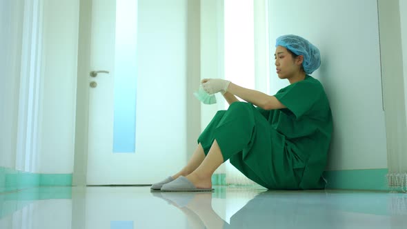 Side view of stressed and overworked female doctor medical worker surgeon sitting on the floor near
