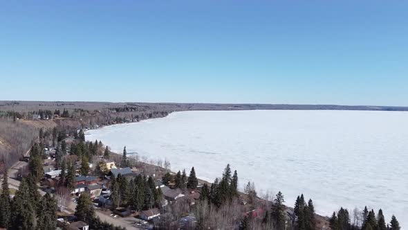 Flying over Small Lake Town Towards Frozen Lake