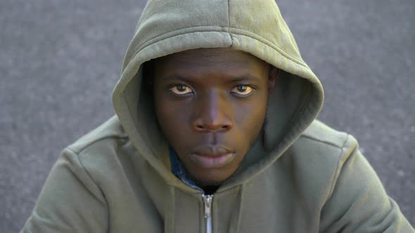 angry serious young black man raises his head and staring at camera