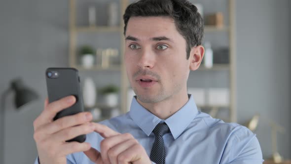 Young Man in Shock While Using Smartphone, Wondering